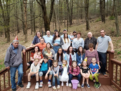 Large family photo on a deck with a wooded background