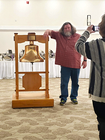 One person from the USS Peterson crew of the 2000's posing next to the ships bell